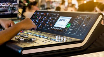 tweaking the EQ of a digital mixing console at a live event