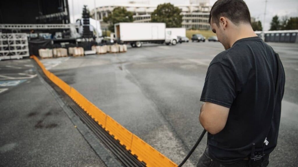 Production technician running audio video cables through protective covering.